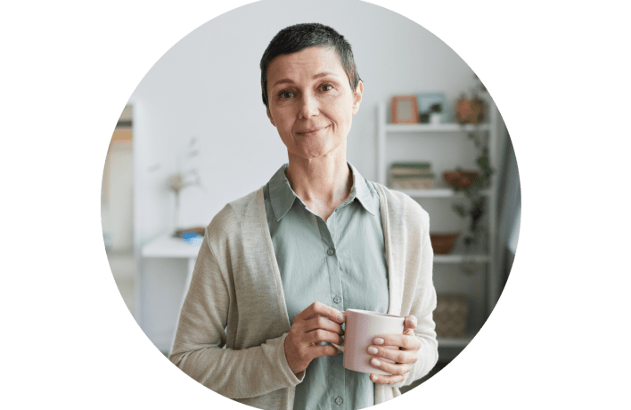 Middle age woman in home with a cup in head, looking into the camera