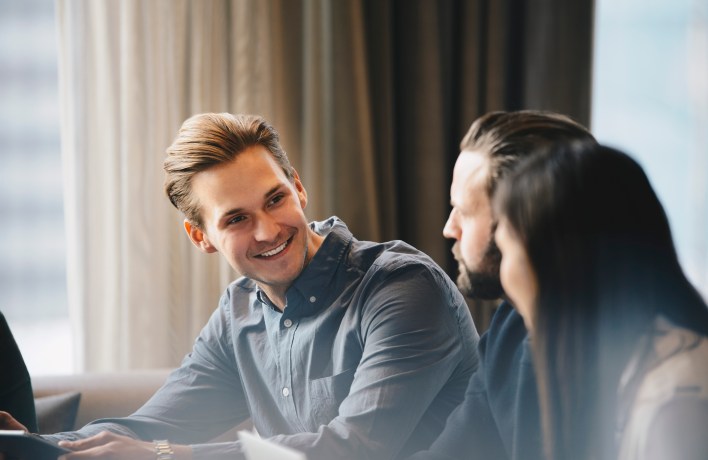 Happy businessman talking to colleagues in brightly lit office
